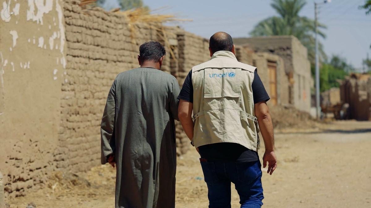 UNICEF worker walks next to another person outside