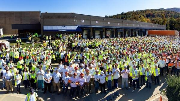 hundreds of employees gather in front of a manufacturing facility
